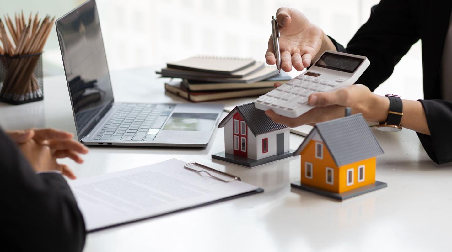 Vue de dessus d'un bureau montrant côte à côte des dossiers de prêt immobilier américain et français avec calculatrice et notes manuscrites